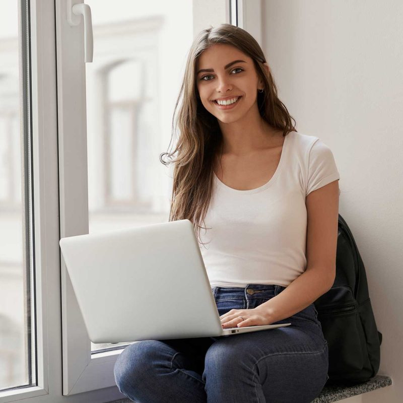 beautiful-female-student-sitting-with-laptop-on-wi-2022-01-18-23-33-22-utc